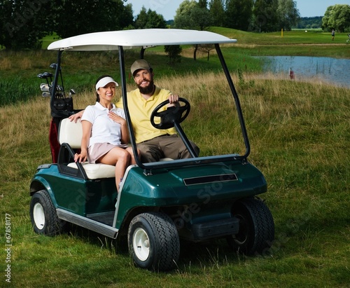Photo: Happy couple driving golf cart Happy couple driving golf cart
