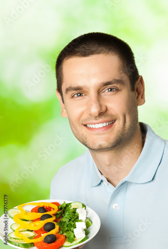 Photo: Happy smiling man with plate of salad, outdoors Happy smiling man with plate of salad, outdoors