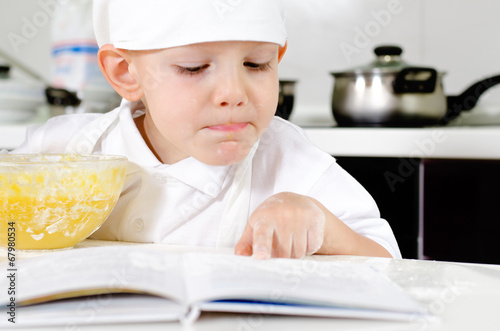 Photo: Small boy learning to cook checking his mixture Small boy learning to cook checking his mixture