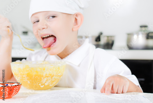 Photo: Small boy learning to cook checking his mixture Small boy learning to cook checking his mixture