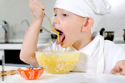 Photo: Cute little chef tasting his cooking Cute little chef tasting his cooking
