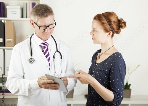 Photo: doctor and a patient woman showing something on tablet pc doctor and a patient woman showing something on tablet pc