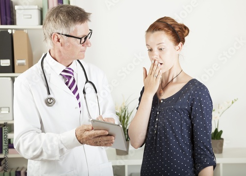 Photo: doctor and a patient looking something on tablet pc and shocking doctor and a patient looking something on tablet pc and shocking