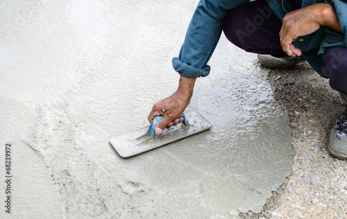Photo: Man's plastering a floor with trowel. Construction worker Man's plastering a floor with trowel. Construction worker