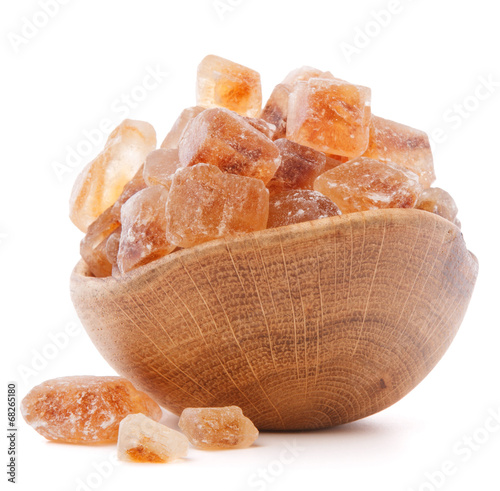 Photo: Brown cane caramelized lump sugar in wooden bowl isolated on whi Brown cane caramelized lump sugar in wooden bowl isolated on whi