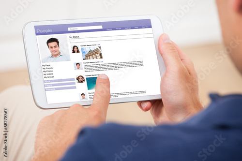 Photo: Man Using Digital Tablet To Chat On Social Site Man Using Digital Tablet To Chat On Social Site