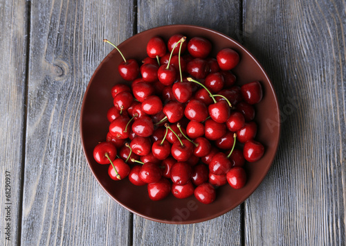 Photo: Sweet cherries on plate on wooden background Sweet cherries on plate on wooden background