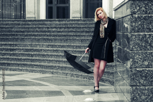 Photo: Young fashion woman with umbrella at the wall Young fashion woman with umbrella at the wall