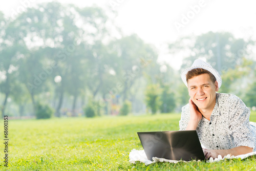 Photo: young man working in the park with a laptop young man working in the park with a laptop