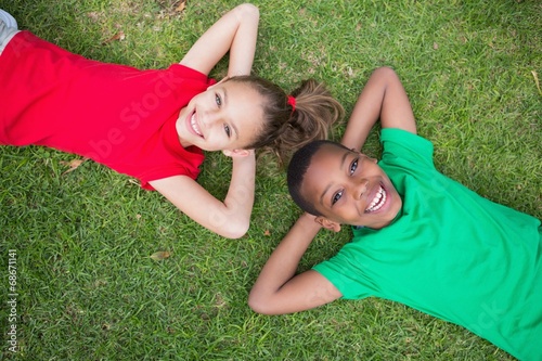 Photo: Cute children smiling at camera outside on the grass Cute children smiling at camera outside on the grass