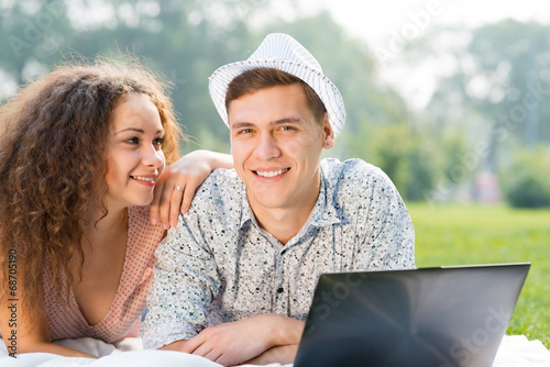 Photo: couple lying together in a park with laptop couple lying together in a park with laptop