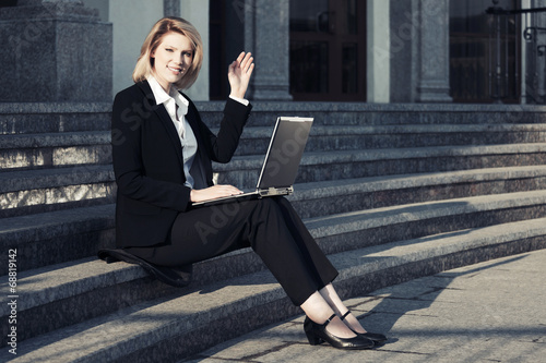 Photo: Young business woman using laptop on the steps Young business woman using laptop on the steps