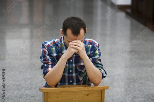 Photo: Handsome young man praying in a church Handsome young man praying in a church