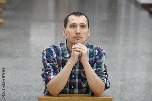 Photo: Handsome young man praying in a church Handsome young man praying in a church