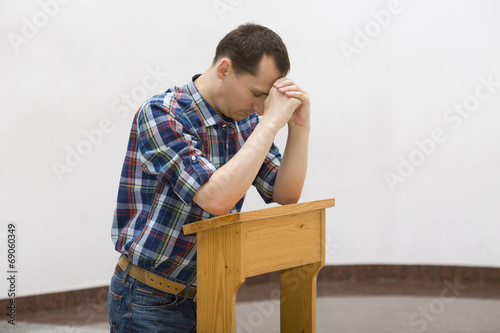 Photo: Handsome young man praying in a church Handsome young man praying in a church