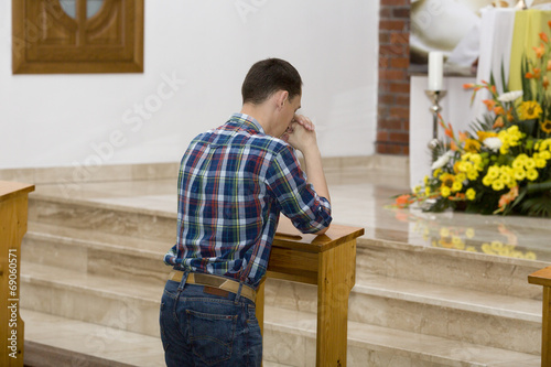 Photo: Handsome young man praying in a church Handsome young man praying in a church