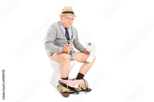 Photo: Senior man pushing hard seated on a toilet Senior man pushing hard seated on a toilet