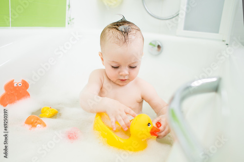 Photo: smiling baby girl taking bath and playing with toys smiling baby girl taking bath and playing with toys