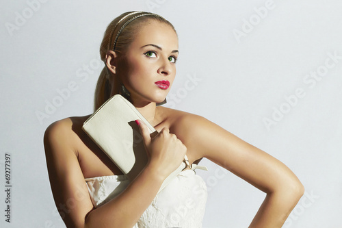 Photo: Beautiful blond woman with white clutch.White bride dress Beautiful blond woman with white clutch.White bride dress
