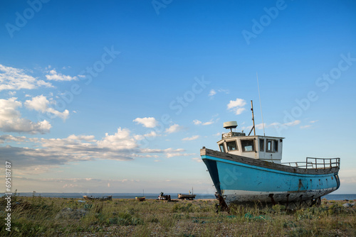 Photo: Abandoned fishing boat on beach landscape at sunset Abandoned fishing boat on beach landscape at sunset