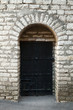 Old stone wall and black metal door, background texture Old stone wall and black metal door, background texture