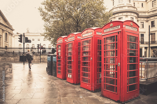 Vintage style red telephone booths on rainy street in London