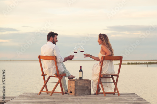 couple drinking red wine at the seaside on a jetty