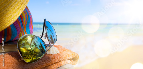 Straw hat, bag and sun glasses on a tropical beach