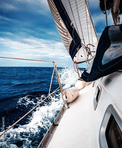  The white sails of yachts on the background of sea and sky in the clouds