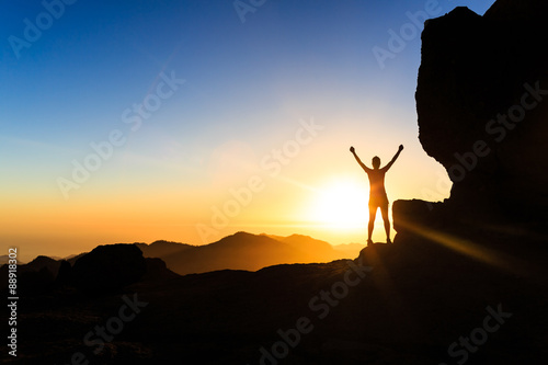Woman climber success silhouette in mountains, ocean and sunset