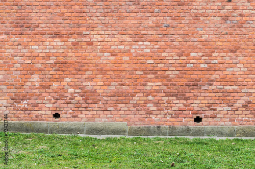 Vintage red brick wall with green grass