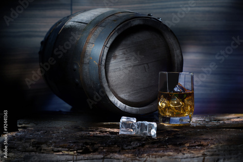 A glass of whiskey in the background the barrels