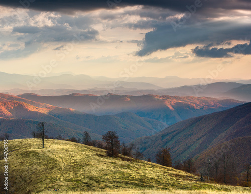 Colorful sunset in the autumn mountains.Tourist tents near forest.