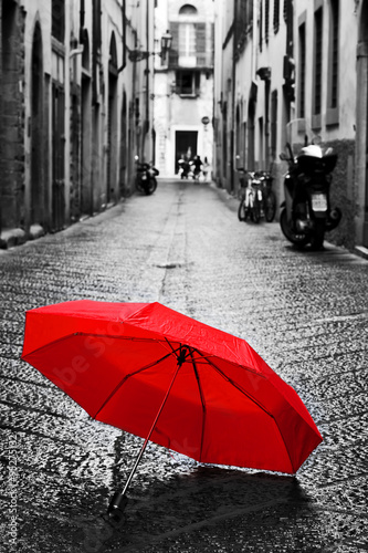 Fototapeta Red umbrella on cobblestone street in the old town. Wind and rain