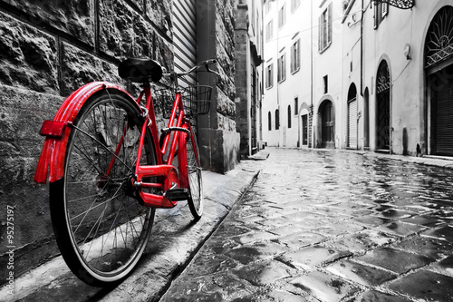  Retro vintage red bike on cobblestone street in the old town. Color in black and white