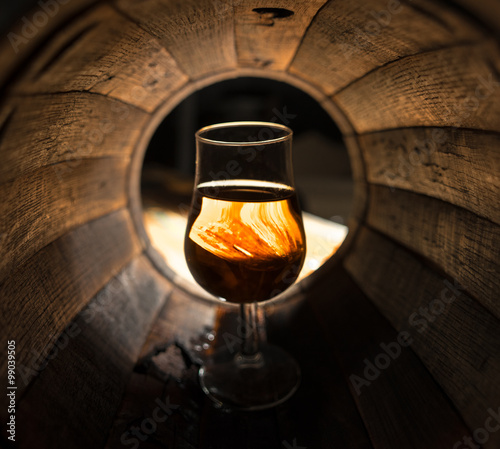 A glass of whiskey in oak barrels