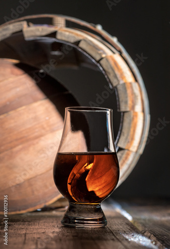 A glass of whiskey on the oak barrel