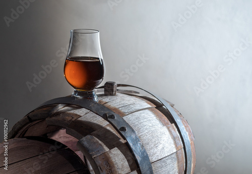 A glass of cognac on an oak barrel