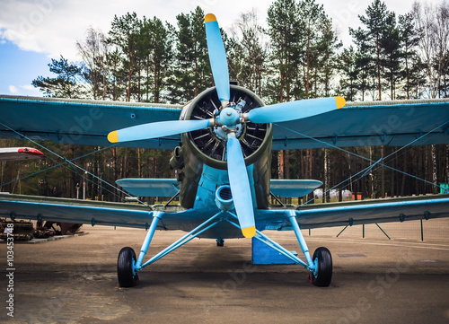 Fototapeta Blue airplane with propeller. Vintage biplane. Front view, with the side of the fuselage. Old retro plane close-up.