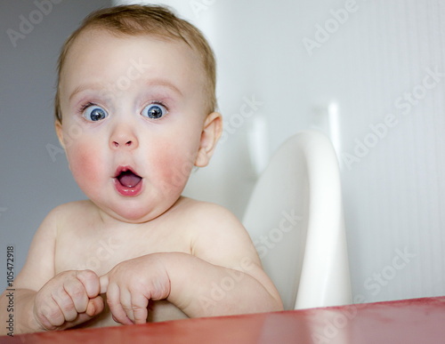surprised kid sitting at table. child's eyes widened and mouth opened in amazement. copy space for your text