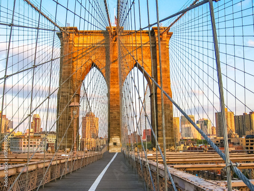  Spectacular views of the Brooklyn Bridge with all its characteristic metal wires and the pedestrian walkway at sunset, New York, United States.