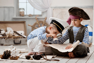 Boys dressed as a pirate captain and read travel map