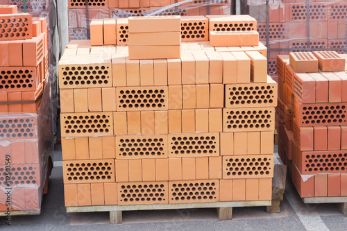 Pallets of perforated yellow and red bricks on warehouse