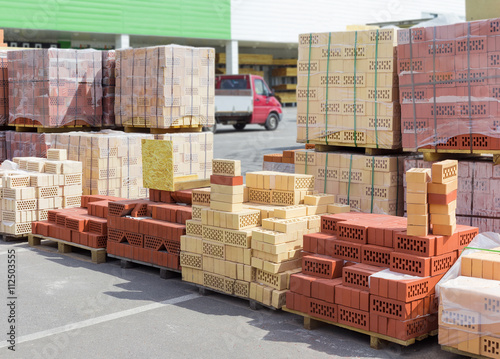 Pallets of perforated red and yellow bricks on warehouse