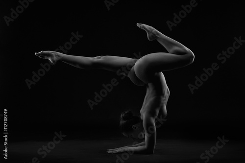 Plakat Akt sztuki. Idealne elastyczne sexy ciało młodej kobiety na czarnym tle. Vrischikasana lub poza skorpion