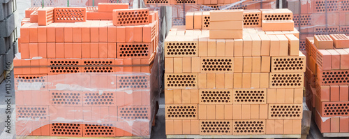Pallets of perforated yellow and red bricks on warehouse
