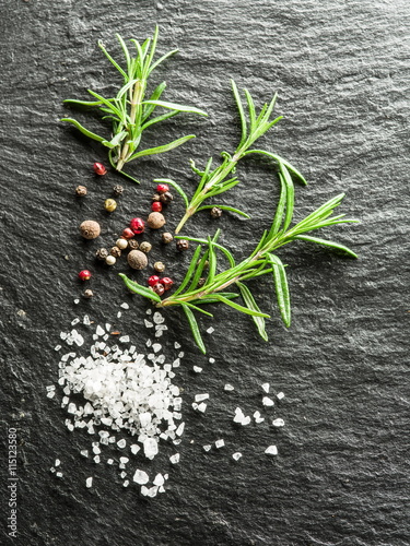Salt, rosemary and peppercorns on the graphite board.