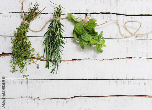  Thyme, rosemary and mint hanging on twine over white wood