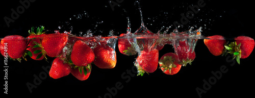  Strawberries splashing into water on a black background