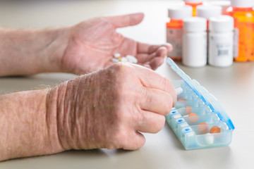 Elderly man sorting daily medication into a pill box.